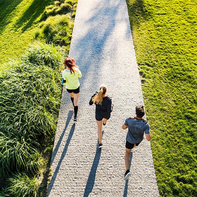 3 people jogging on pathway